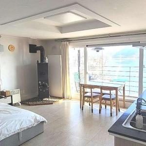 a bedroom with a bed and a table and a kitchen at Interlaken Stay in Gapyeong