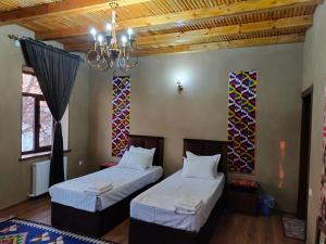 2 łóżka w pokoju z żyrandolem w obiekcie Darvozai Samarkand guest house w Samarkandzie