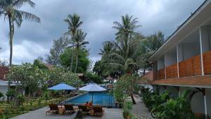 a couple sitting under umbrellas next to a swimming pool at Blue Marlin Air in Gili Islands
