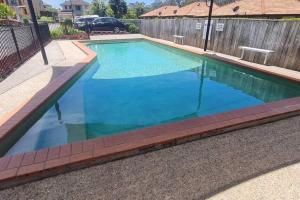 a swimming pool with blue water in a backyard at Happy Haven at Eight Mile in Brisbane