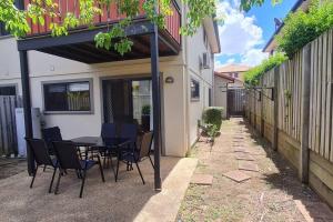 um pátio com uma mesa e cadeiras sob uma pérgola em Happy Haven at Eight Mile em Brisbane