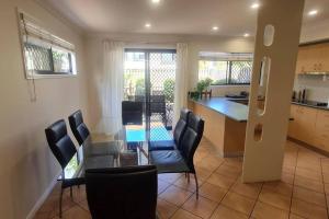 a kitchen and dining room with a glass table and chairs at Happy Haven at Eight Mile in Brisbane