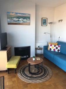 a living room with a blue couch and a table at Royal Zeezicht Oostende in Ostend