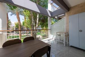 a room with a table and chairs on a balcony with trees at Kings suite at Royal Park Eilat in Eilat