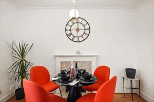 una sala da pranzo con sedie rosse, tavolo e orologio di 5 guests 3 beds 1 sofa bed Lewisham a Londra