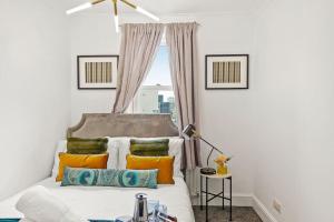 ein Schlafzimmer mit einem Bett mit orangefarbenen und grünen Kissen in der Unterkunft 5 guests 3 beds 1 sofa bed Lewisham in London