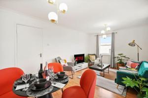 ein Wohnzimmer mit einem Tisch und orangefarbenen Stühlen in der Unterkunft 5 guests 3 beds 1 sofa bed Lewisham in London