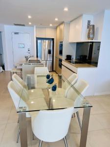 comedor con mesa de cristal y sillas blancas en Soul Luxury Apartment’s, en Gold Coast