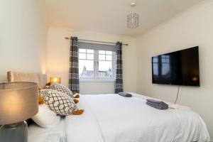 a bedroom with a bed with a flat screen tv at 4 Bedroom Townhouse in Stirling in Stirling