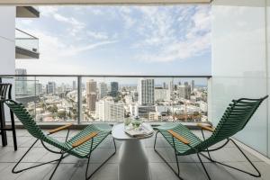 balcón con mesa, sillas y vistas a la ciudad en Beautiful 2br in midtown w sea view, pool and parking by Sea N' Rent, en Tel Aviv