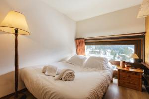 1 dormitorio con 1 cama con lámpara y ventana en Résidence Grand Roc - Campanules 415 - Happy Rentals, en Chamonix-Mont-Blanc