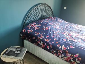 a bed with a blue blanket with flowers on it at Namaste Home, charming holiday home in Saint Rémy de Provence - South of France in Saint-Rémy-de-Provence