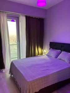 ein lila Schlafzimmer mit einem großen Bett und einem Fenster in der Unterkunft Batışehir residence in Istanbul