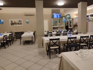 una sala da pranzo con tavoli e sedie bianchi e palloncini di Hotel Residence Eden a Mozzagrogna
