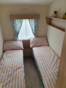 two beds in a small room with a window at Billing Aquadrome in Great Billing