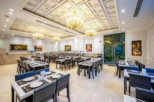 a dining room with tables and chairs and chandeliers at Acnos Grand Hotel in Ho Chi Minh City
