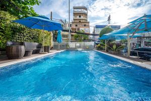 a swimming pool with blue umbrellas on top of a building at Acnos Grand Hotel in Ho Chi Minh City