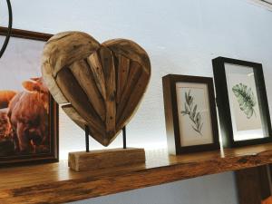 a shelf with three pictures and a wooden heart at Dorfplatz Loft - großzügig & modern nur 10Min von Rothenburg odT in Schrozberg