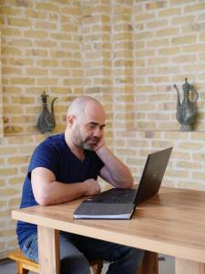 un homme assis à une table avec un ordinateur portable dans l'établissement OLD SAFARI HOTEL make yourself at home, à Boukhara