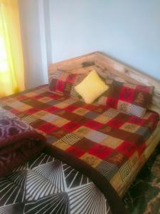 a bed with a checkered blanket and pillows on it at Ajit Homestay, Darjeeling in Darjeeling