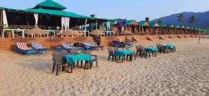 a row of tables and chairs on a sandy beach at Saxony Village Resort in Agonda