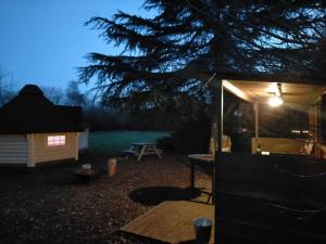 um quintal à noite com uma tenda e uma mesa de piquenique em Oak Tree Escape em Brome