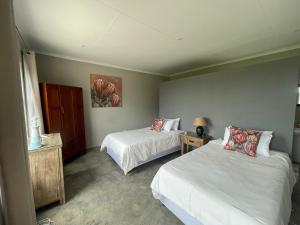 a bedroom with two beds and a table with a lamp at Holbank River Lodge in Ermelo