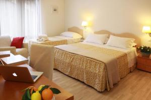 une chambre d'hôtel avec deux lits et un ordinateur portable sur une table dans l'établissement Residenza Giacomuzzi, à Mestre