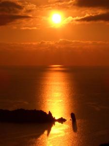 una puesta de sol sobre el océano con el sol en el cielo en Ammiraglio, en Campese