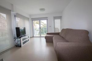 ein Wohnzimmer mit einem Sofa und einem Flachbild-TV in der Unterkunft Moderno y bonito apartamento en primera linea de playa de poniente in Benidorm