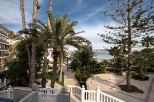 einen Balkon mit Palmen und einem weißen Zaun in der Unterkunft Moderno y bonito apartamento en primera linea de playa de poniente in Benidorm