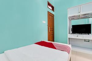 a blue room with a bed and a flat screen tv at OYO 92294 Amole Homestay Syariah in Cilacap