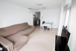 ein Wohnzimmer mit einem Sofa und einem Tisch in der Unterkunft Moderno y bonito apartamento en primera linea de playa de poniente in Benidorm