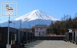 uma montanha coberta de neve no fundo com um sinal em Mt Fuji Glamping VILLA Kawaguchiko em Fujikawaguchiko