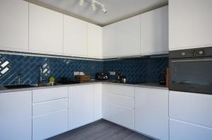 a kitchen with white cabinets and black appliances at Starfish Apartment in Beer