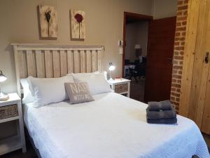 a bedroom with a large white bed with a pillow at Kiepersol Cottages - Cottage A in East London