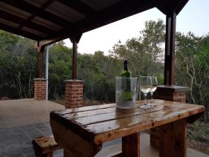 a wooden table with a bottle of wine and a glass at Kiepersol Cottages - Cottage A in East London