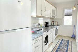 eine Küche mit weißen Schränken, einer Waschmaschine und einem Trockner in der Unterkunft Ozy Apart Bayındır in Kaş