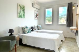 a white bedroom with two beds and a couch at Ozy Apart Bayındır in Kas