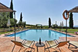 a swimming pool with chairs and a bottle of wine at Via della Stella in Valiano