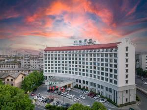 Un gran edificio blanco con coches aparcados en un estacionamiento. en Guilin Bravo Hotel-The Grand Wing, en Guilin