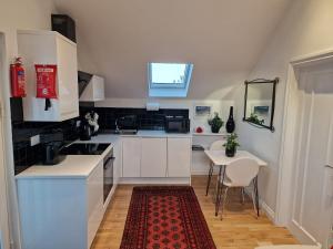 uma cozinha com armários brancos e uma mesa com um tapete vermelho em Blue Hills Luxury Apartment, Coast Front, Parking em Falmouth