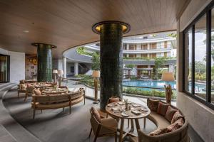 hotelowy hol ze stołami i krzesłami oraz basenem w obiekcie AYANA Segara Bali w mieście Jimbaran