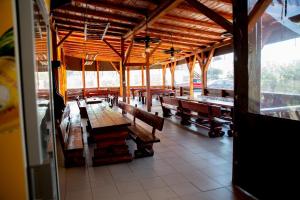 un restaurant avec des tables et des bancs en bois dans un bâtiment dans l'établissement Motel Moara Veche, à Săcălăşeni