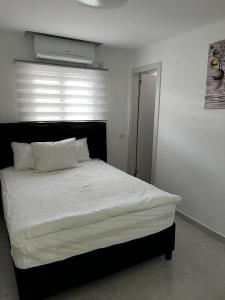 a bedroom with a white bed with a black headboard at מישל נופש ,יותם 6003 in Eilat