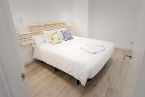 un letto bianco con cuscini sopra di Apartamentos Soria Suites a Soria