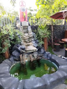 a small pond in a garden with a statue at JLF Inn in Daraga