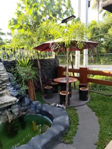 a garden with a pond and a table and umbrella at JLF Inn in Daraga