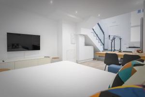 Habitación blanca con mesa, TV y escaleras. en Apartamentos Soria Suites, en Soria
