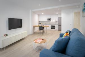 a living room with a blue couch and a kitchen at Apartamentos Soria Suites in Soria